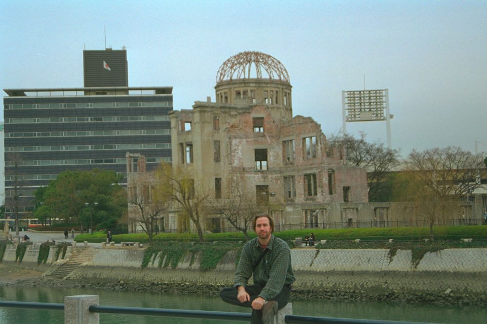 A dork sits in front of the remnants of the bank destroyed by the world's first use of the atomic bomb on a civilian population.