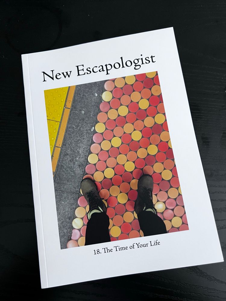 A copy of issue 18 of the magazine New Escapologist, an A5 perfect bound mag with a cover showing a pair of feet on a red and yellow dotted stretch of pavement.