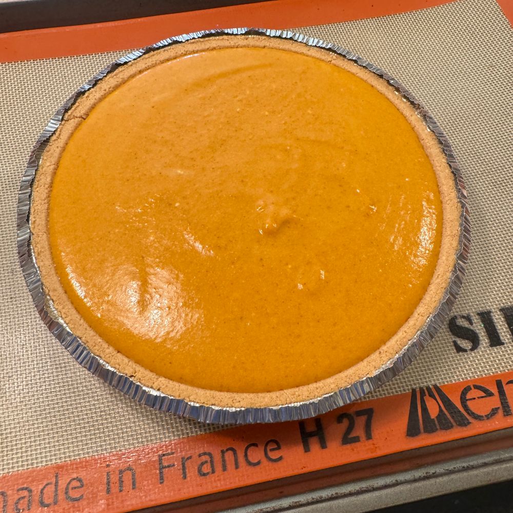 Photo of a pumpkin cream pie in a graham cracker crust on a baking sheet 