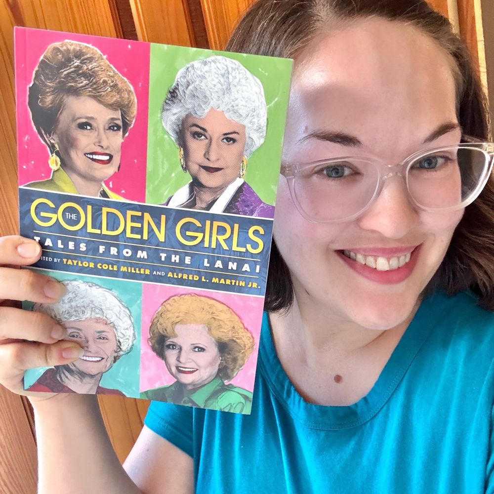 Selfing holding a copy of the book The Golden Girls: Tales from the Lanai next to my face 