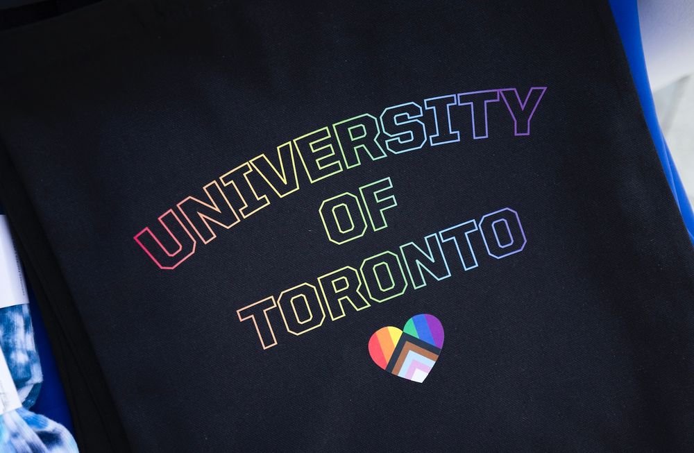 University of Toronto t-shirt with rainbow text and a progress pride flag in the shape of a heart.