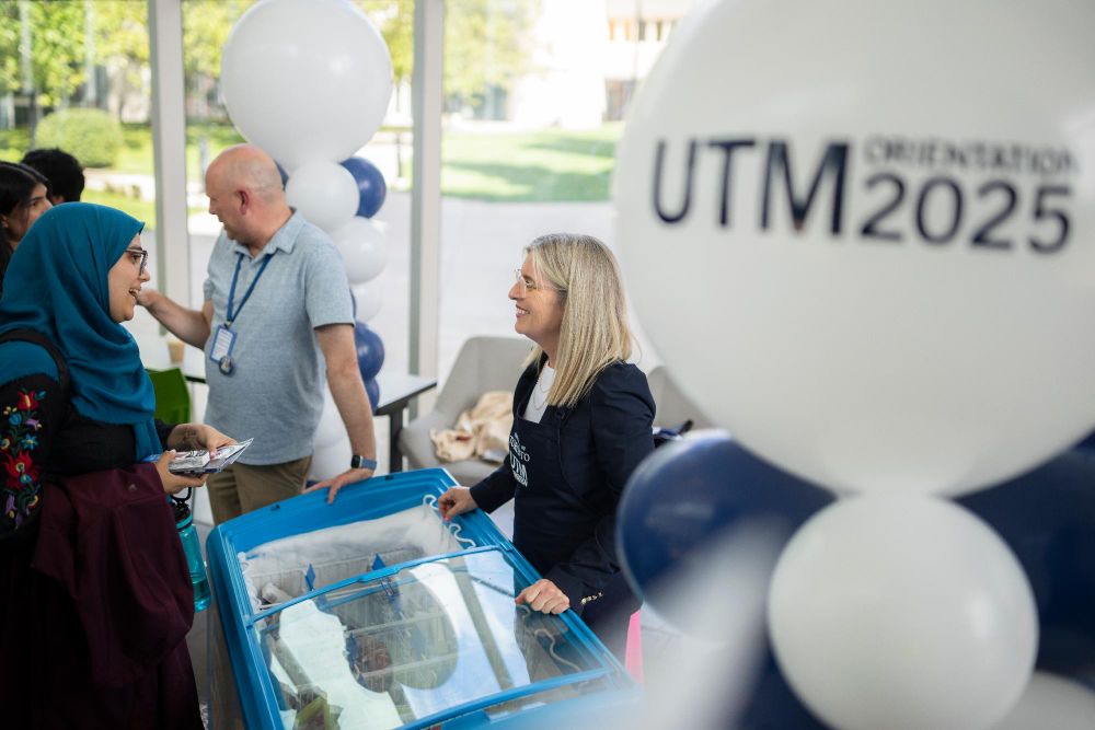 U of T President Melanie Woodin with staff and students at a UTM Orientation 2025 event, surrounded by balloons, near an ice cream cart.