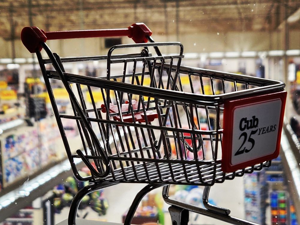 A miniature shopping cart that says Cub 25 Years, overlooking the inside of a grocery store.