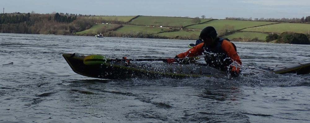 A man in a sea kayak paddling with his hands.