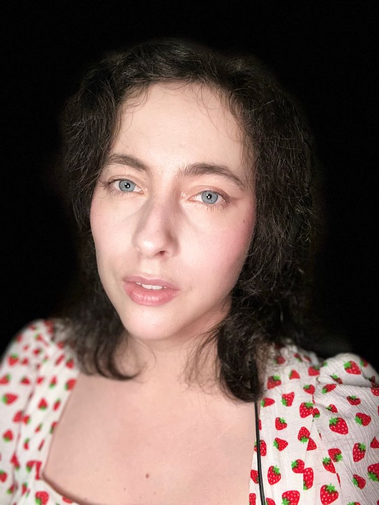 Selfie of Amberosesia, who has light blue eyes, short dark brown slightly curly hair.