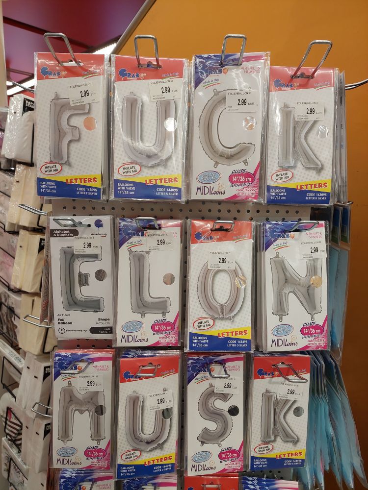 Photo of a bunch of cards with letters on them at a store.

The letters in order are F, U, C, K, E, L, O, N, M, U, S, K