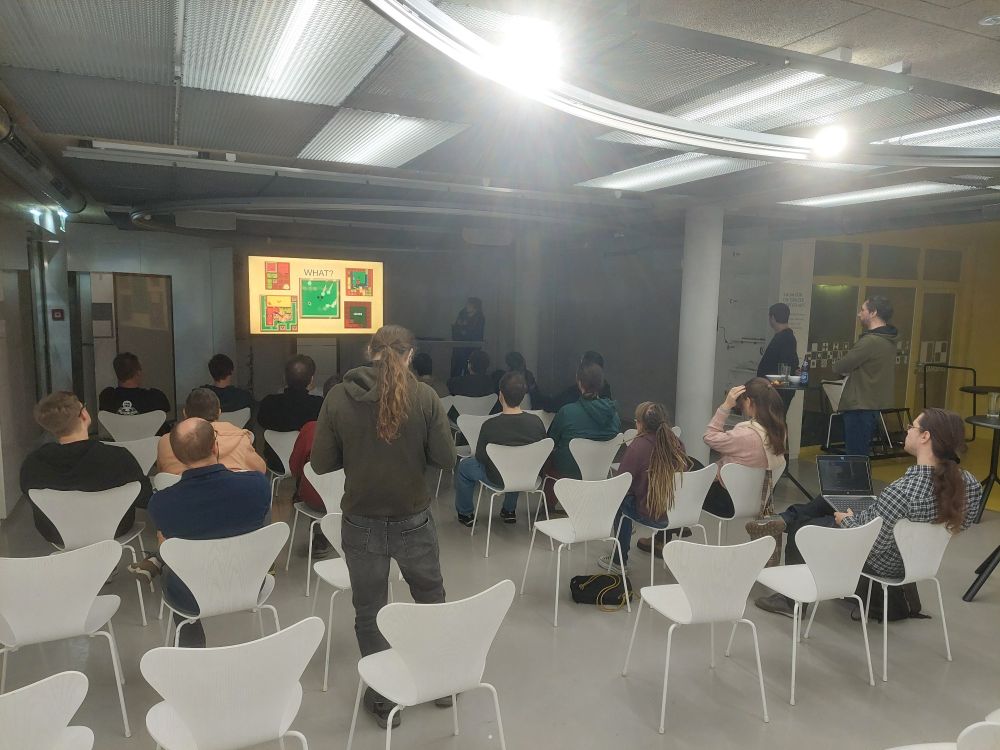 A bunch of people sitting on chairs and watching a presentation.