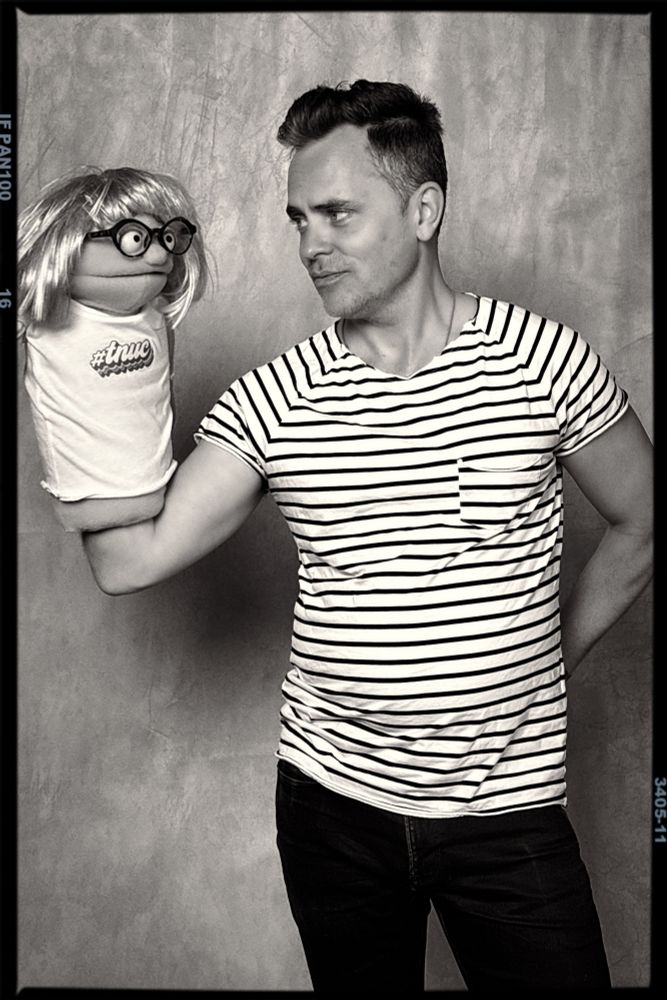 A black & white photo from The New Uni-Con convention in June 2025. David Jenkins in very pirate-esque stripped t-shirt, holding the muppet version of Captain Amy. 