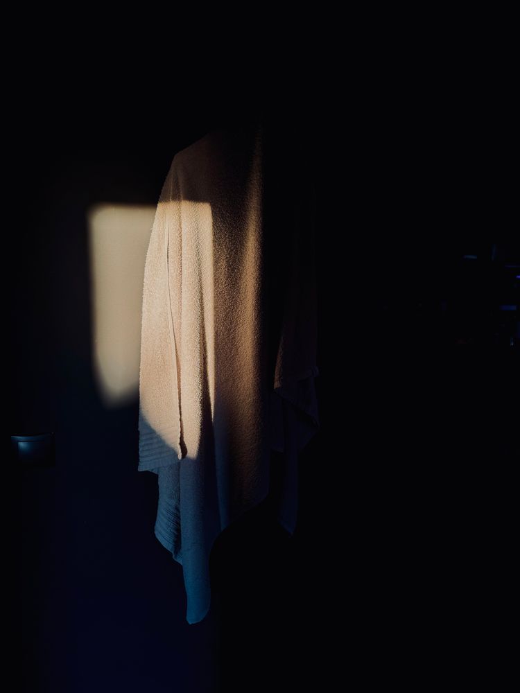 Man sieht ein weißes Handtuch, dass von einem warmen Licht angescheint wird, ansonsten ist das Bild dunkel