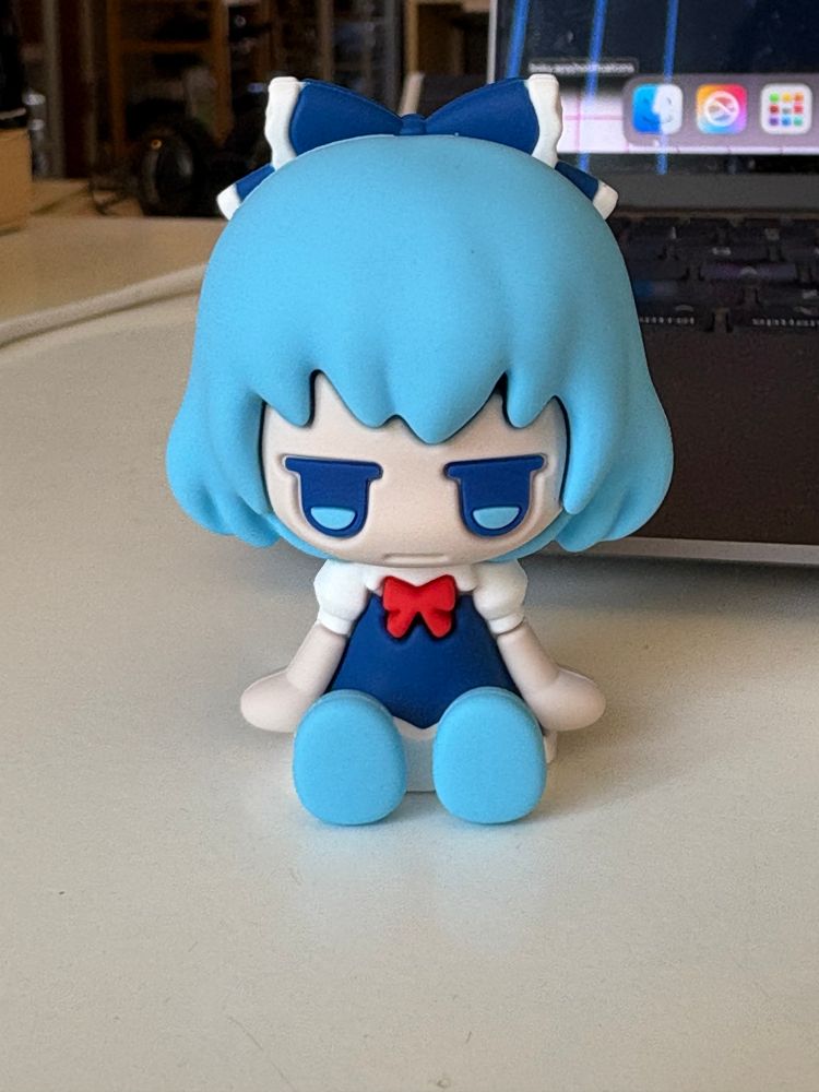 A little figure of Cirno from Touhou, sitting on my coffee table next to my MacBook.