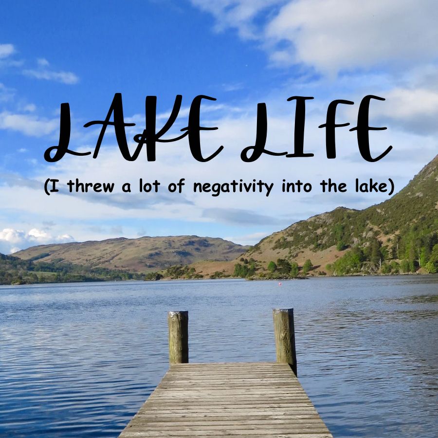 a stock photo of a mountain lake with a dock in the foreground. text reads “LAKE LIFE” in a stereotypical handwritten sign font and “(I threw a lot of negativity into the lake)” in bold comic sans