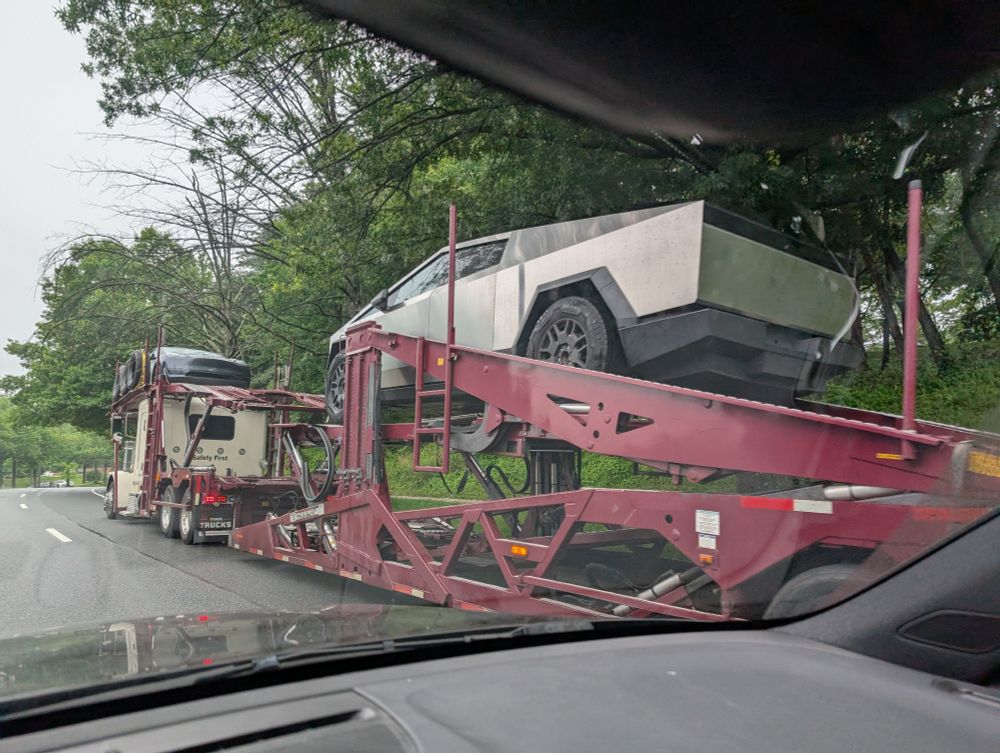 Car carrier outside dealership, with two Teslas.