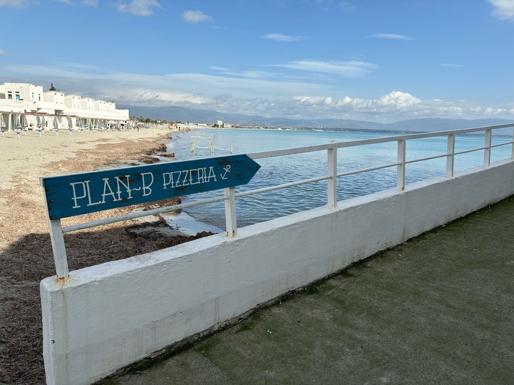 Beach scene with a sign that says Plan B Pizzeria, Cagliari, Sardinia 