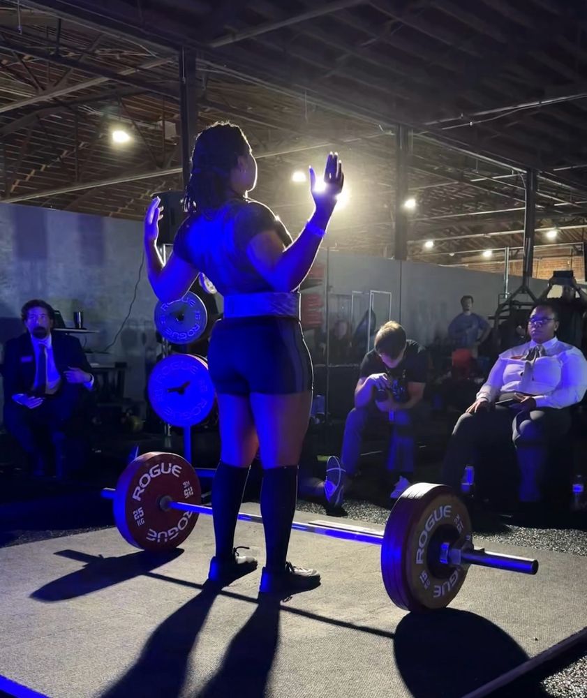 Female powerlifter standing on a platform at a competition preparing to deadlift