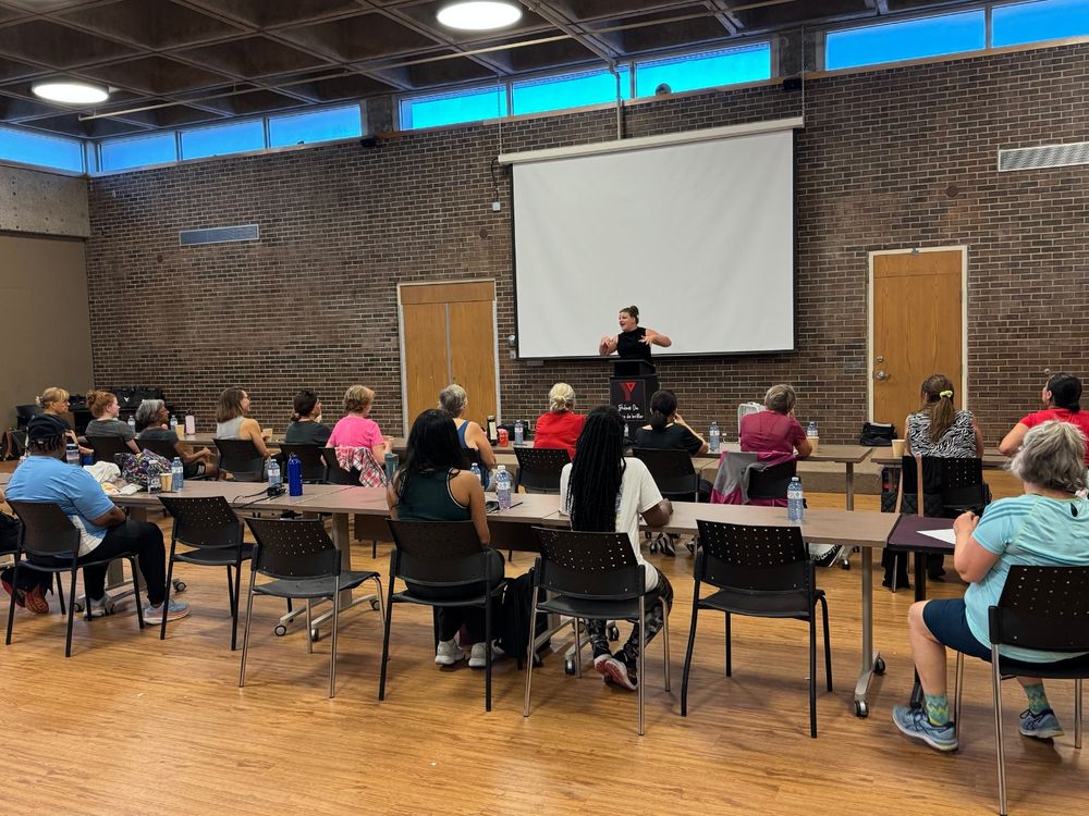 Programs participants sitting at desks and listening to presenter Savanna Symons.