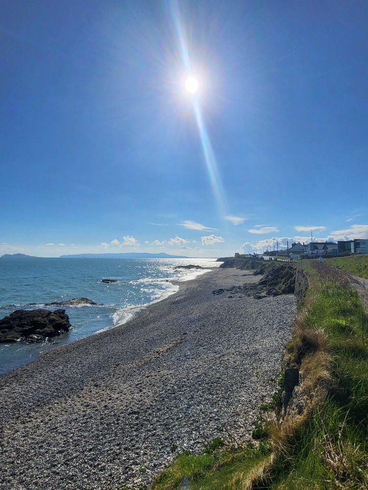 A sea view with a sandy shore. A blue sky with sun