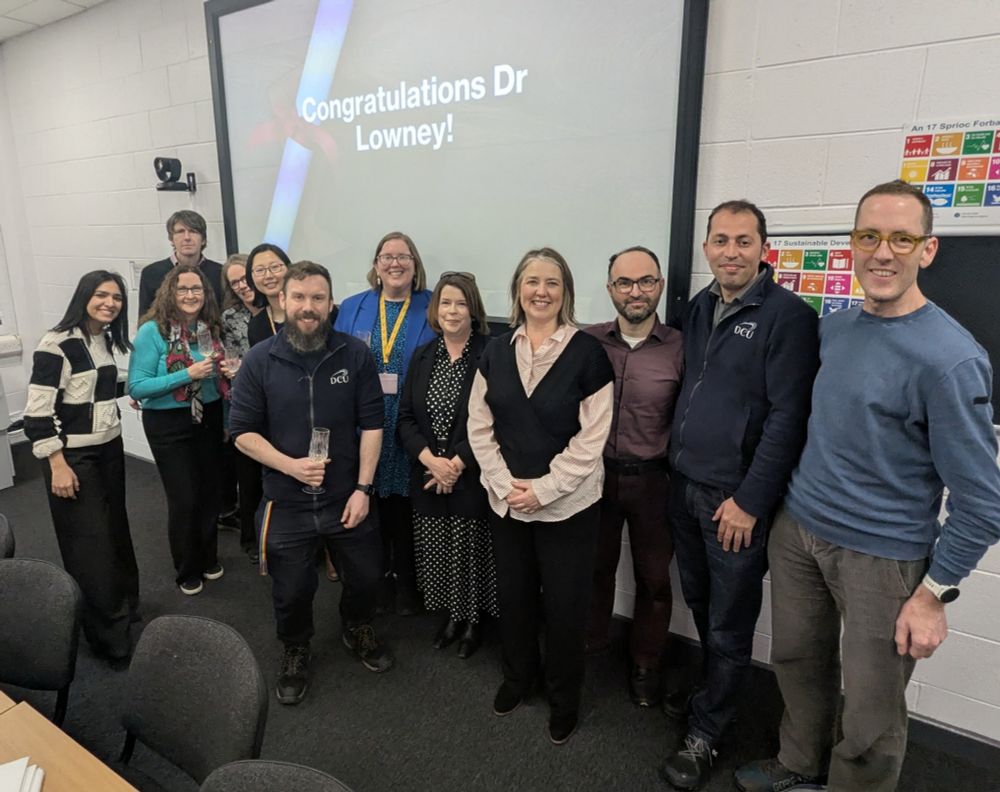 Group of people in front of screen with words congratulations Dr Lowney