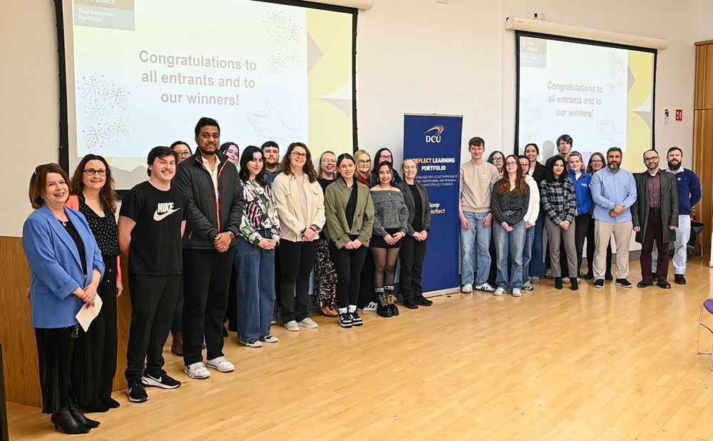 Students standing in front of a screen stating congratulations to all entrants and winners
