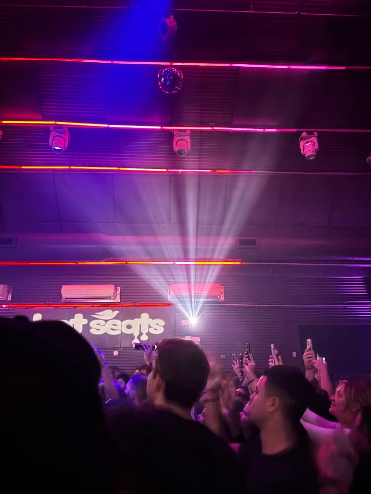 A scene from people dancing at a purple lit club, with what is clearly the Dove soap logo in the background. 