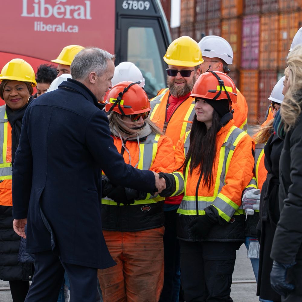Mark Carney shakes hands with a worker at the Port of Montreal.