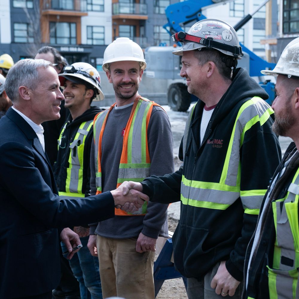 Prime Minister Mark Carney shakes hands with construction workers during an announcement on housing in Edmonton, Alberta.