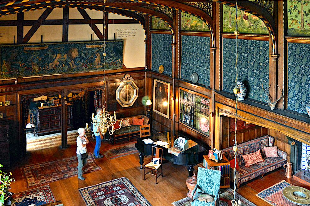 Wooden flooors, Morris wall coverings, and the Morris tapestry "The Forest" along one wall, with a few people admiring the furniture and decor.
