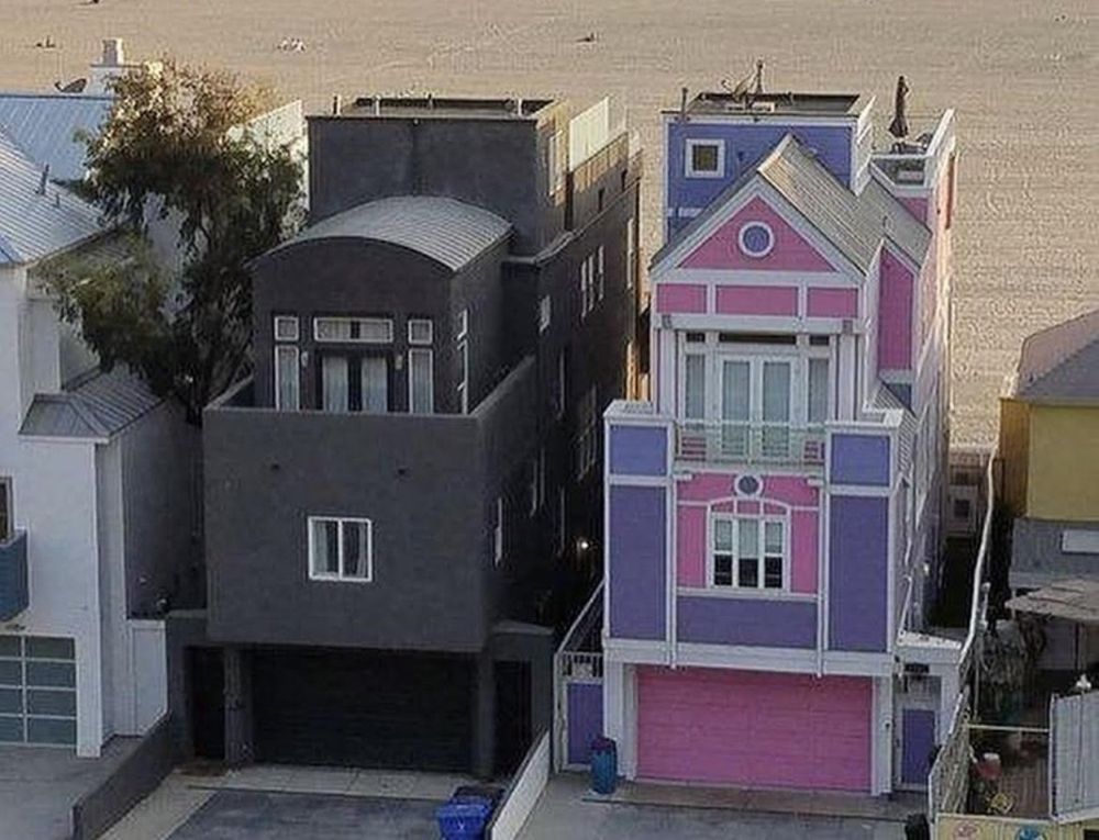 Image of two houses next to each other. The left is painted all black and the right is pink, white, and purple.