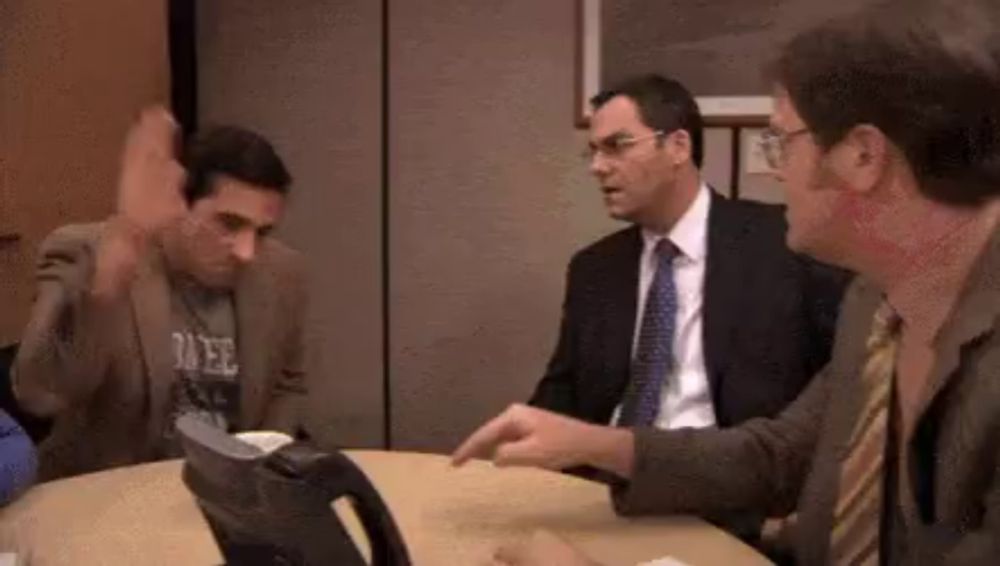 three men in suits and ties are sitting around a table .