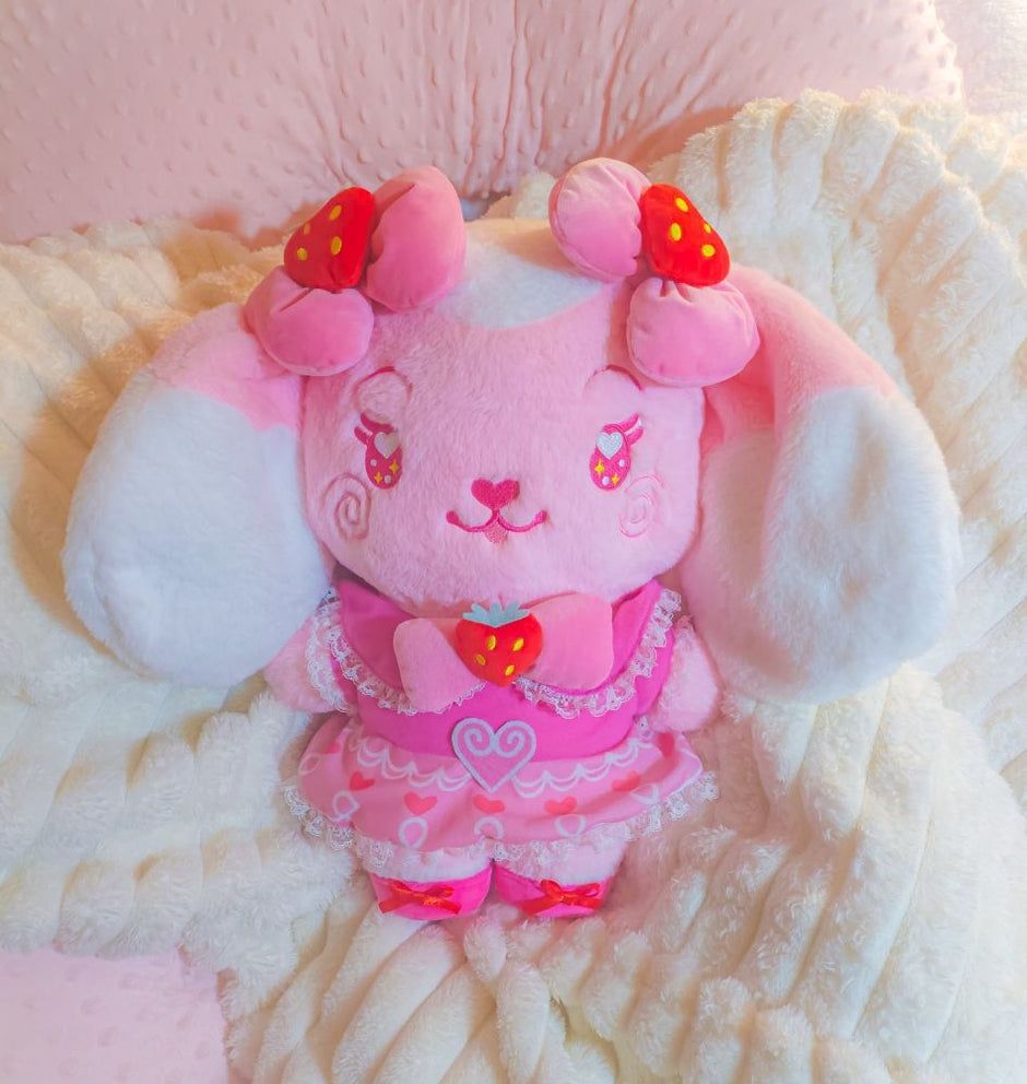 A stylized bipedal mostly light pink and white lop bunny character plushie wearing an ornate pink dress with strawberry embellishments and bows.