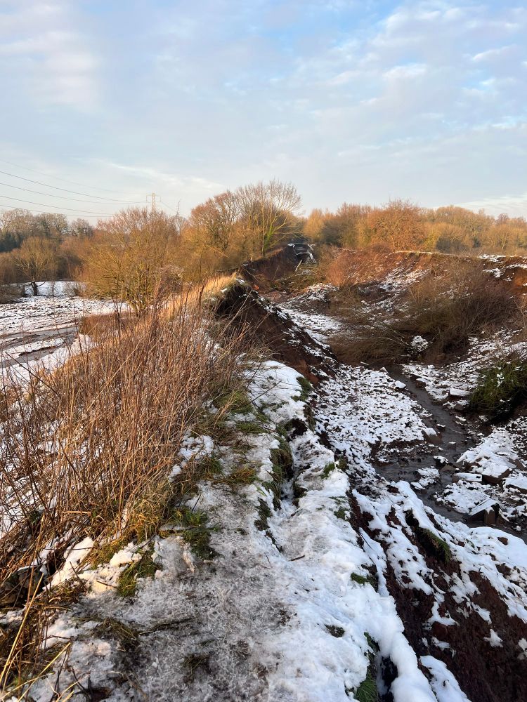 Showing a snowy landscape which is the Bridgewater Canal drained and eroded after embankment breach