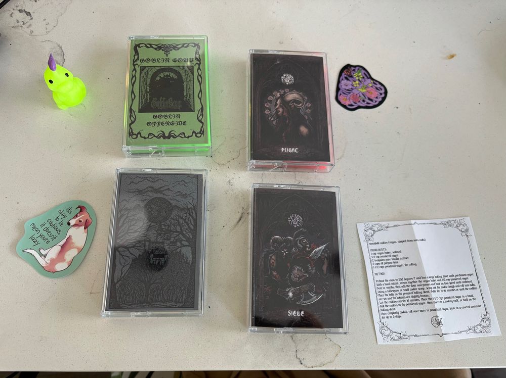 A picture of 4 tapes as well as 2 stickers, a little squishy dinosaur thing, and a recipe, on a dirty white countertop 