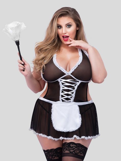 A curvy white femme-presenting model is wearing a traditional black and white French Maid Lingerie outfit, holding a white feather duster up in one hand, with their other hand close to her mouth which is open in a wide smile.