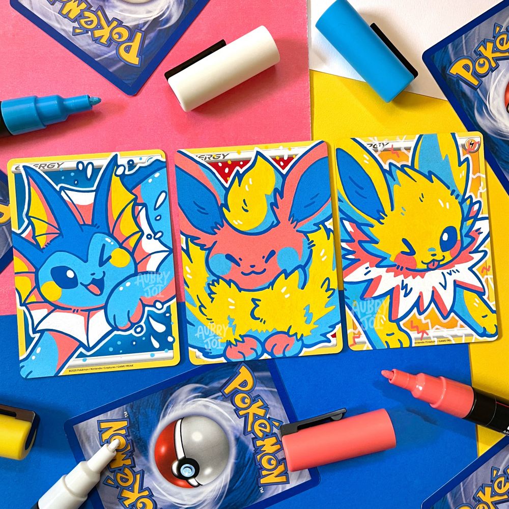 Three Pokemon Energy Cards with original artwork painted onto them. Vaporeon is painted on a Water Energy; Flareon on a Fire Energy; and Jolteon on an Electric Energy. All paintings are done in a limited color palette.