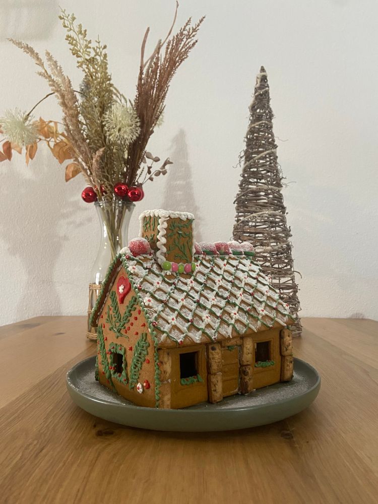 Una casita de galletas de jengibre decorada con chuches, galletas y 
dibujillos de plantas y flores. Tiene azúcar glas por encima para que parezca nieve. Está un poquito precaria y amorfa, pero es cuqui.