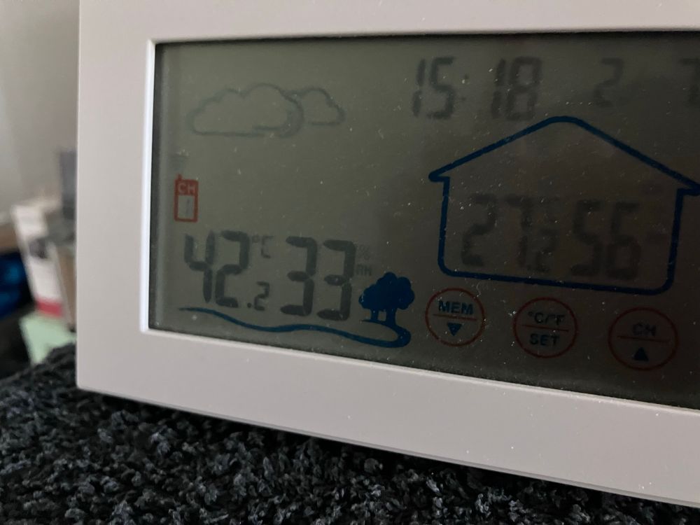 Ein Thermometer zeigt links eine Außentemperatur von 42,2 °C und Luftfeuchtigkeit von 33%. Rechts Innentemperatur 27,2°C und 56% Luftfeuchtigkeit. (Die Uhr stimmt nicht, es war 16.18 Uhr 😉)