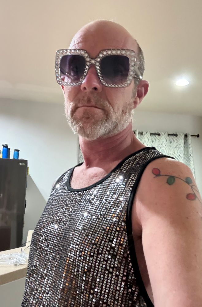 Jake in a sparkly silver tank top and sunglasses with sparkly silver rims