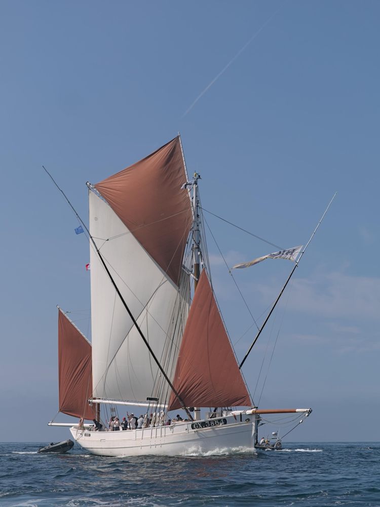 Photograph of a sailing fishing ship. The side beams are attachement for nets.