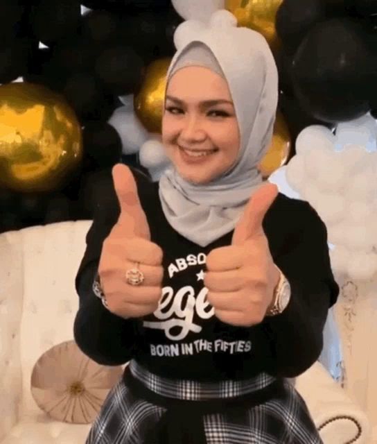 a woman in a hijab is giving a thumbs up sign