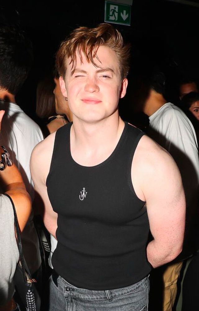 Kit Connor squinting at camera wearing a black tank top