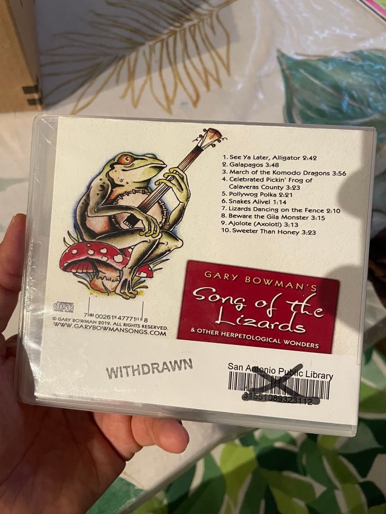 A photograph of the rear of a CD album called songs of the lizards by Gary Bowman. It was available at the San Antonio public library