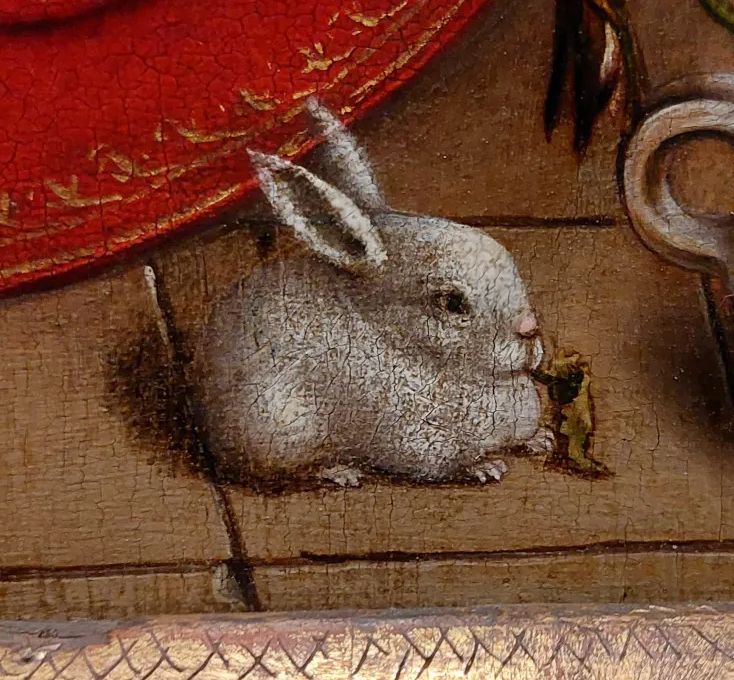 a small, painted rabbit with an abnormally large head chewing on a leaf 