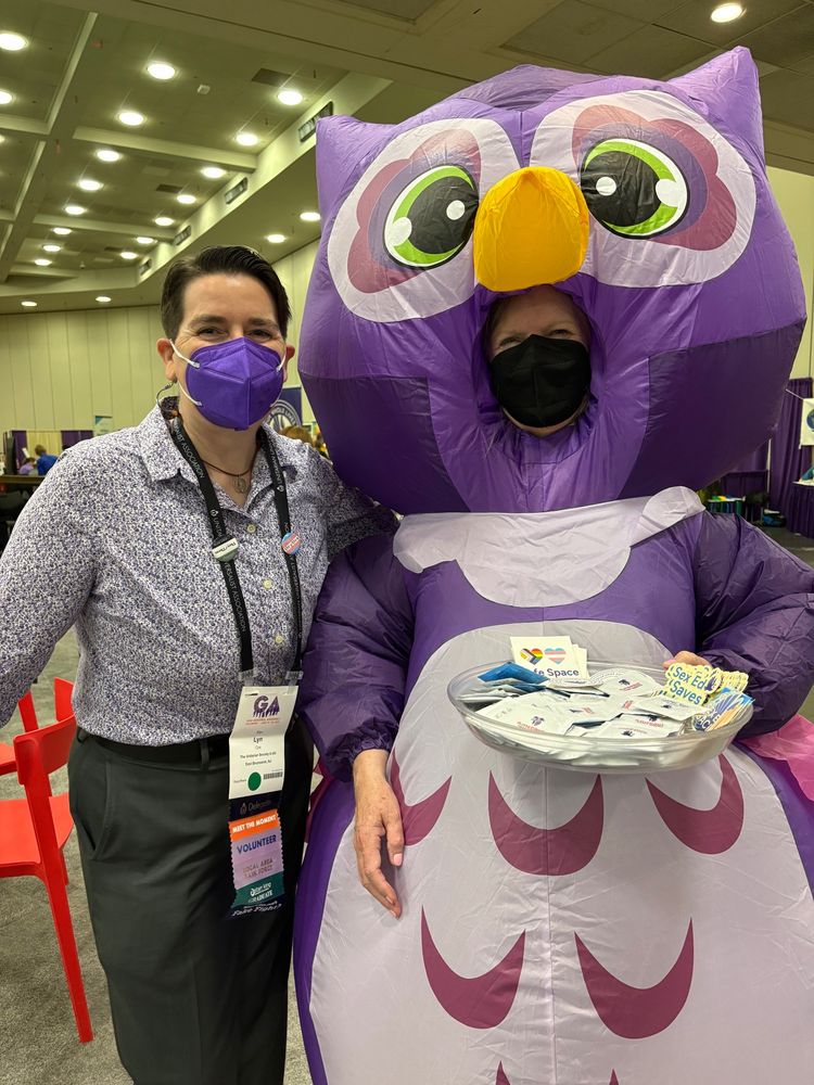 The blogger poses with a person wearing a purple inflatable owl costume that matches the Our Whole Lives logo