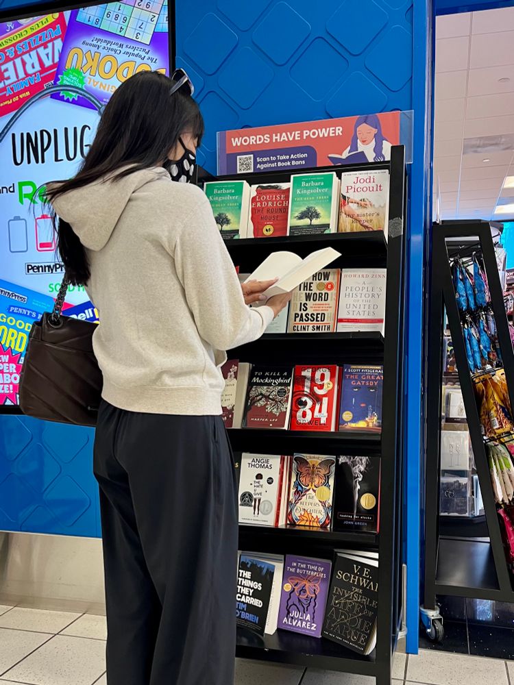 A woman reading in front of a bookshelf.