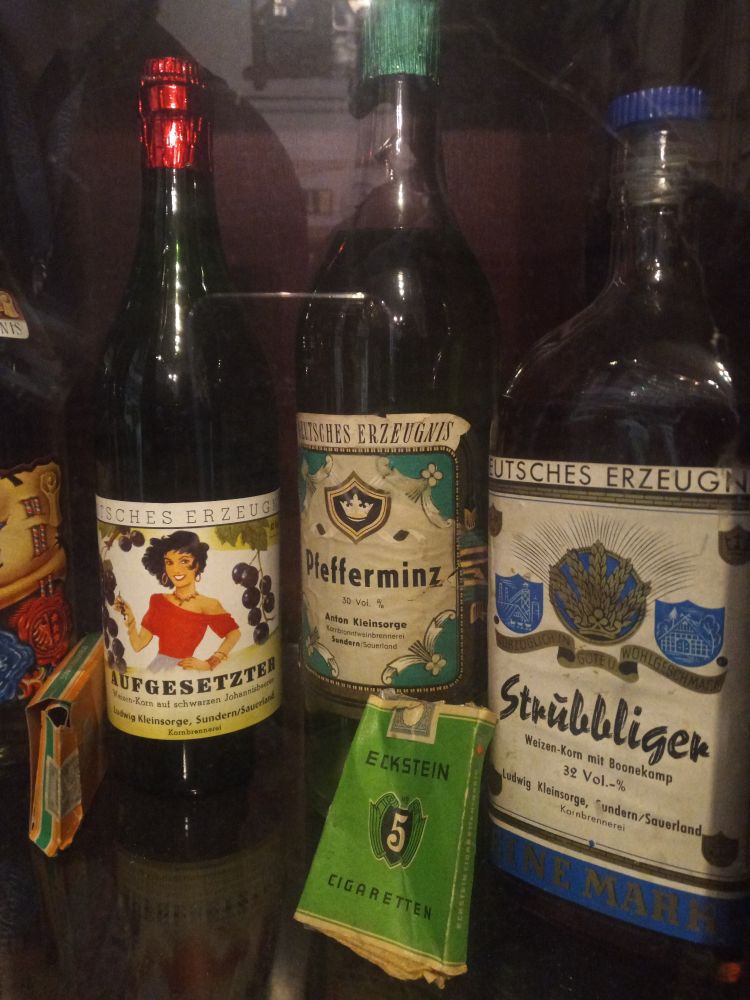 Historische Flaschen von Produkten der alten Kornbrennerei: Aufgesetzter (eine rot gekleidete Frau auf dem Label), Pfefferminz und Strubbliger