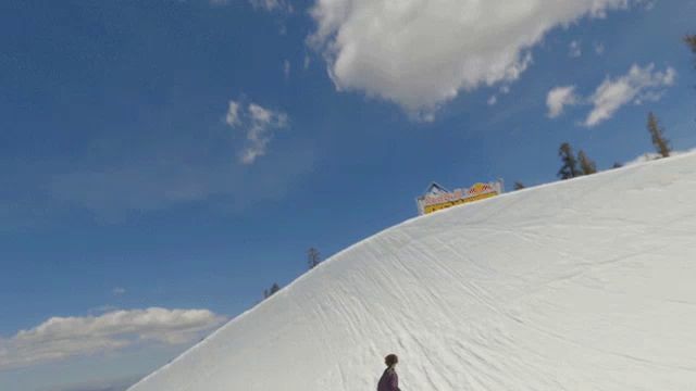 a person skiing down a snow covered slope with a red bull sign in the distance