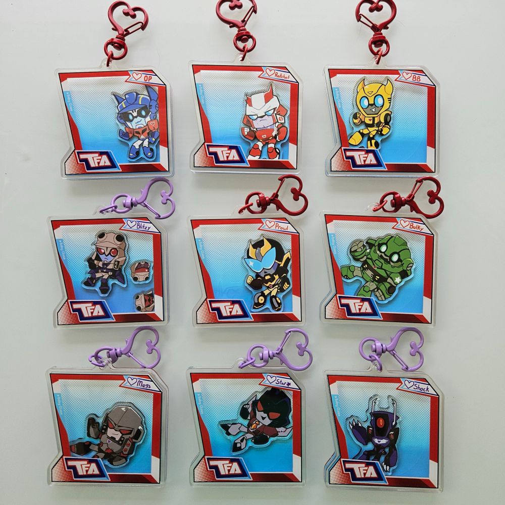 A photo of shaker charms of characters from Transformers Animated. The style of the outside of the charm is made to look like the boxes the toys for the series came in.
The top row has Optimus Prime, Ratchet, and Bumblebee. The second row has Blitzwing, Prowl, and Bulkhead. And the third row has Megatron, Starscream, and Shockwave.