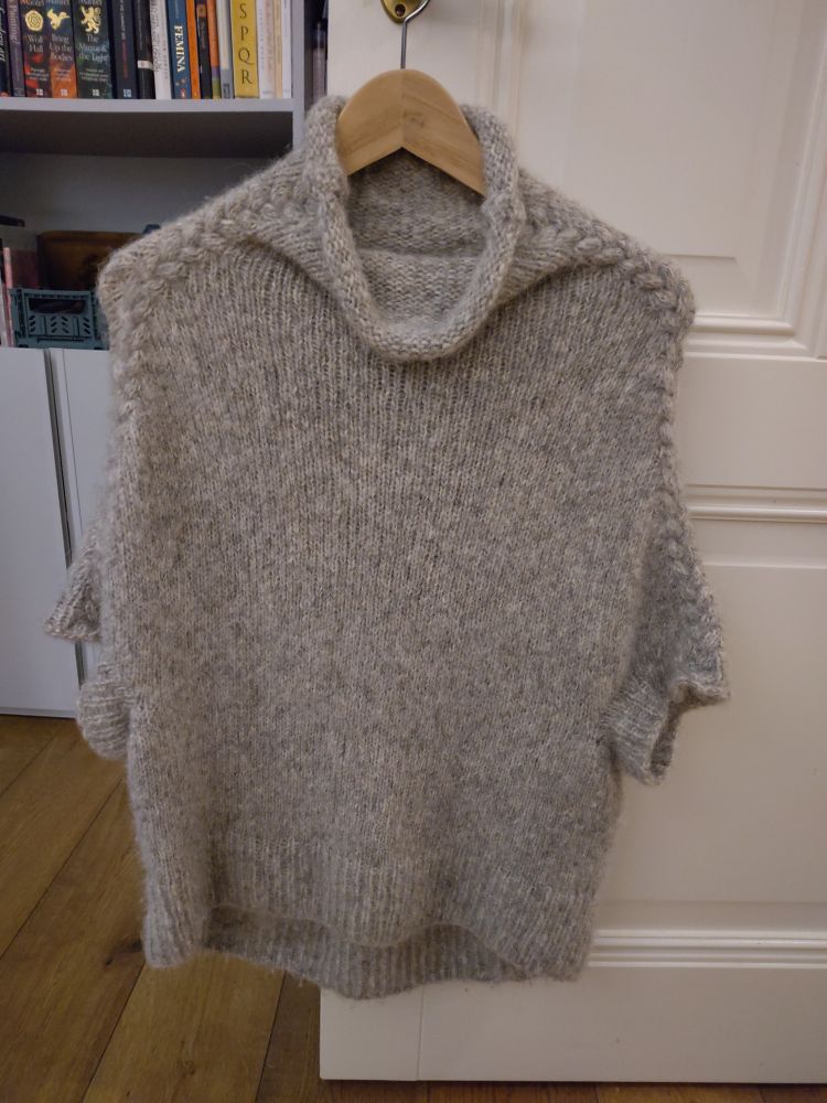 Pale grey (looks beige in photo) hand-knitted jumper in a soft alpaca/ cotton mix yarn. High neck, very low dropped shoulder and longer at back than front. 