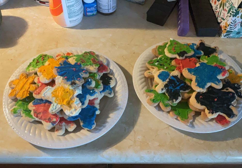Multi colored icings on sugar cookies shaped like Christmas trees, gingerbread men, and snowflakes.