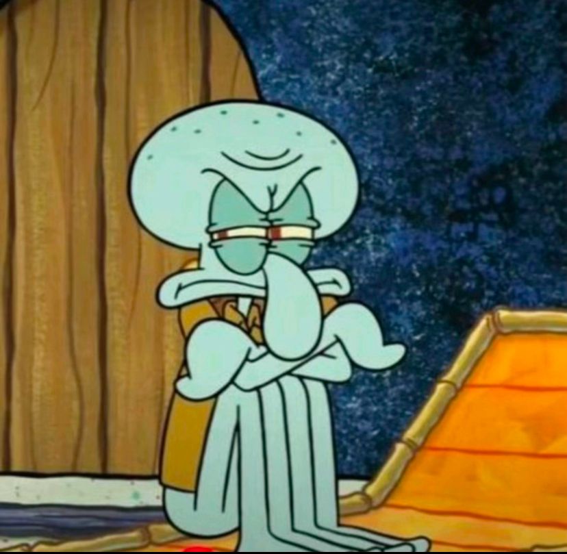Squidward sitting down and looking angry with his arms crossed and his knees pulled up to his chest 