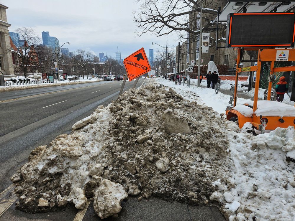 A dirty snow bank covers the Queen's Park bike lane south of bloor